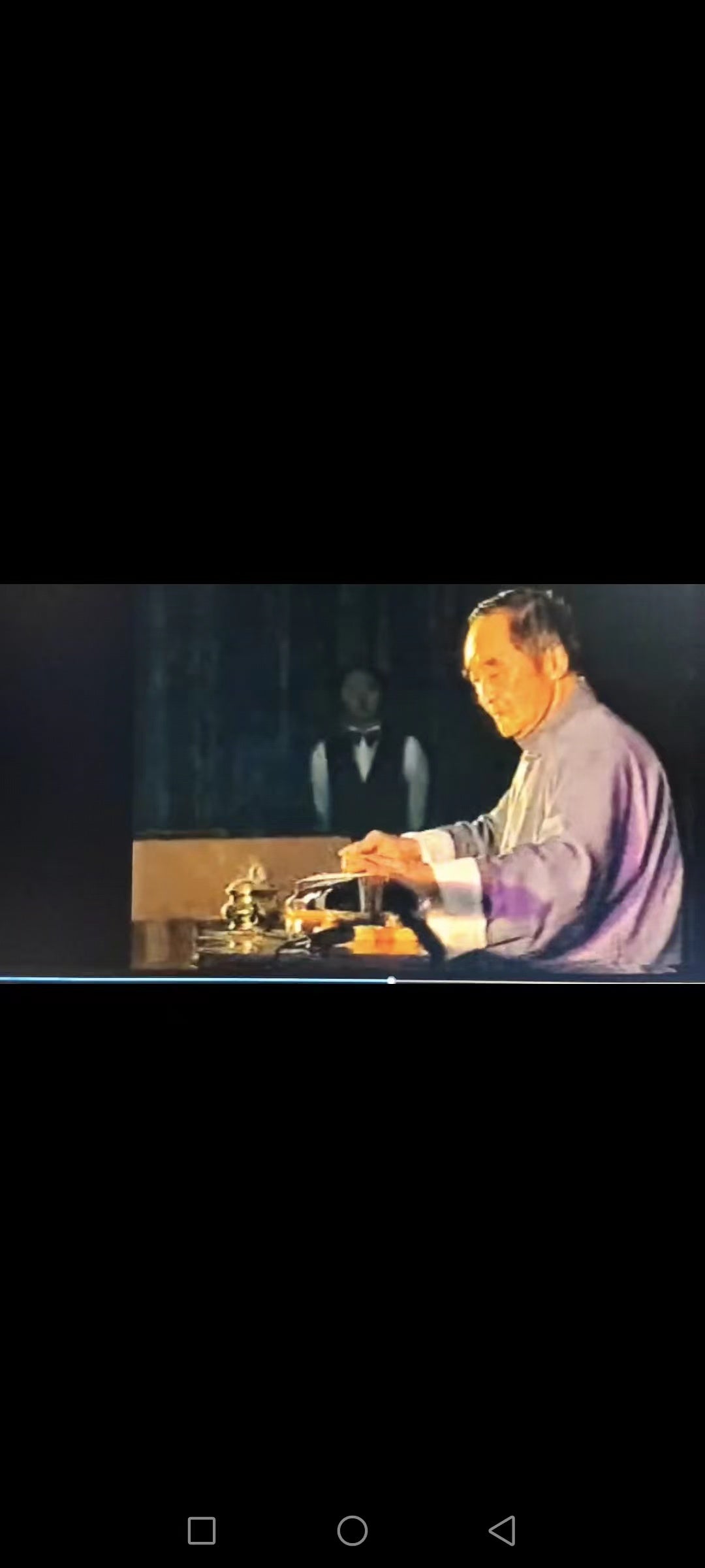 Master Mei Yueqiang performing on the guqin under stage lighting, his hands resting gently on the strings