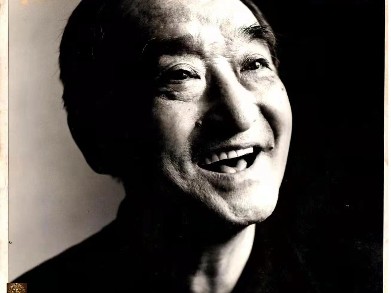 Guqin master Mei Yueqiang, black and white portrait photograph, smiling with a warm and open expression