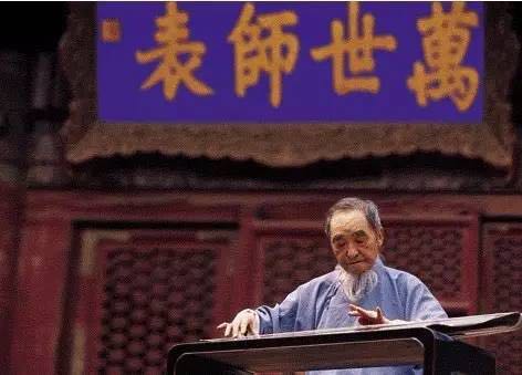 Mei Yuqiang playing the guqin beneath a plaque reading 'Teacher of Ten Thousand Generations'